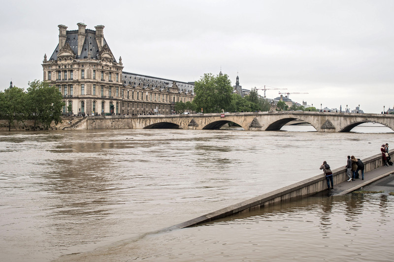 epa05344496 People watch the Louvre museum from a submerged dock on the left bank of the Seine river in Paris, France, 03 June 2016. Floods and heavy rain drenched about a quarter of the French territory over several days. EPA/CHRISTOPHE PETIT TESSON