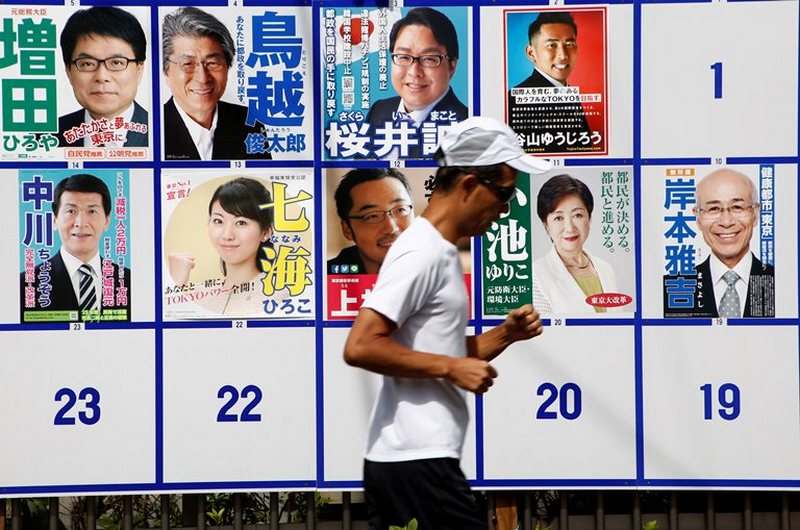 A jogger runs past candidate posters for the Tokyo Governor election in Tokyo, Japan, July 31, 2016. REUTERS/Kim Kyung-Hoon