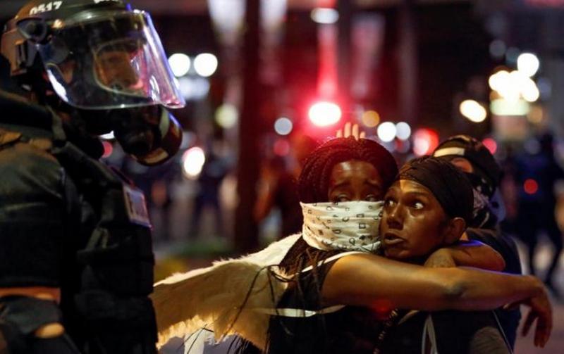 Two women embrace while looking at a police officer in uptown Charlotte, NC during a protest of the police shooting of Keith Scott, in Charlotte, North Carolina, U.S. September 21, 2016. REUTERS/Jason Miczek