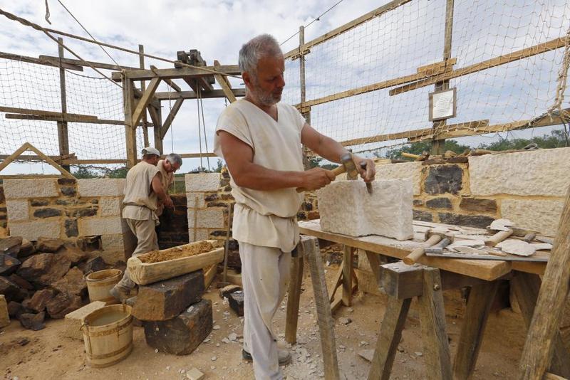 Stonecutter and massons work at the construction site of the Chateau de Guedelon. REUTERS/Jacky Naegelen