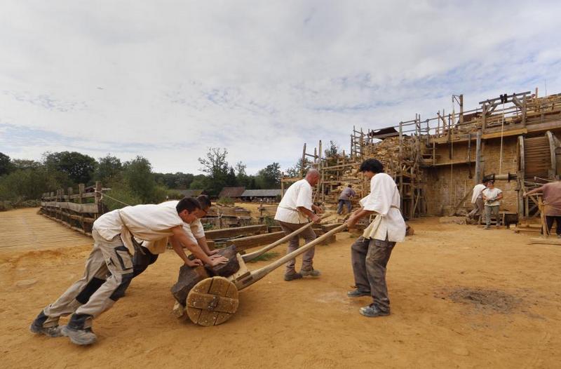 Workers carry stones at the construction site of the Chateau de Guedelon. REUTERS/Jacky Naegelen