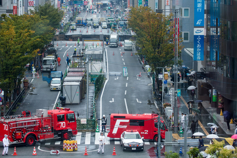 epa05621788 Police and fire brigade vehicles block access to a large sinkhole on a road in central Fukuoka, southwestern Japan, 08 November 2016. No injuries are reported so far by local medias as the sinkhole is causing blackouts and disrupting traffic. Authorities have evacuated surrounding buildings in fear of further damage.  EPA/HIROSHI YAMAMURA