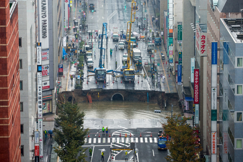 epa05621785 A large sinkhole cuts off an avenue in central Fukuoka, southwestern Japan, 08 November 2016. According to local media reports, the sinkhole has caused blackouts and disrupted traffic. Authorities have evacuated surrounding buildings in case of further damage. There were no immediate reports of damage or injuries.  EPA/HIROSHI YAMAMURA