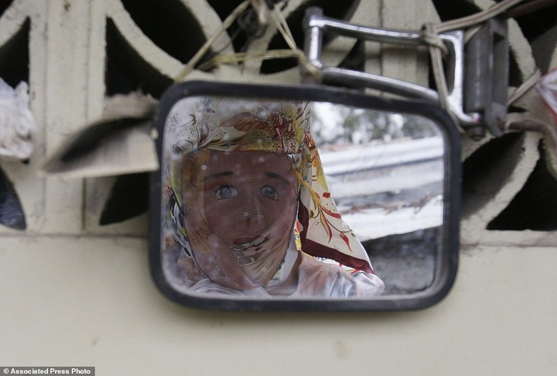 A woman dressed for "La Diablada" festival, sees her reflection on a mirror, in Pillaro, Ecuador, Friday, Jan. 6, 2017. Local legend holds that anyone who adopts a costume for the celebration and wears it at the event six years in a row will have good luck. (AP Photo/Dolores Ochoa)
