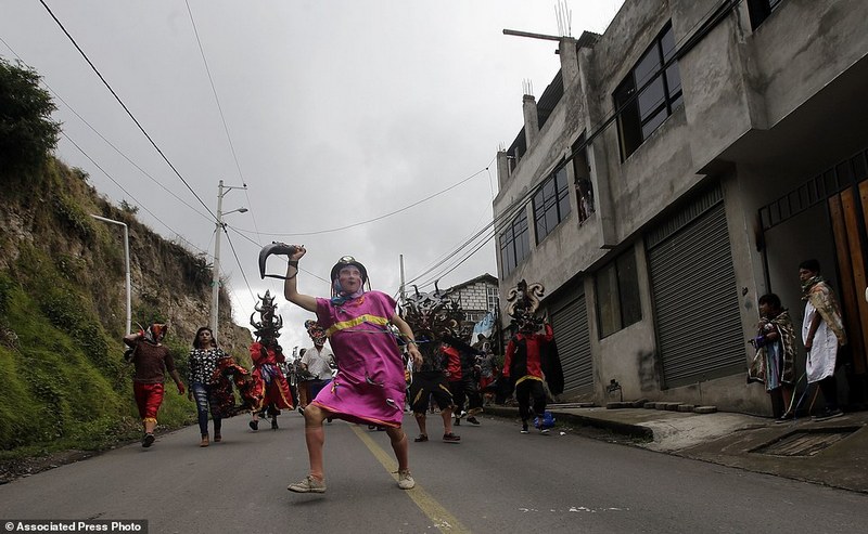 A man dressed in character heads the parade of devils on their way to Pillaro to be part of "La Diablada" festival, in Pillaro Ecuador, Friday, Jan. 6, 2017. The devils wear huge masks, red suits, black cloaks, and elaborate wigs. Some dancers dress as street sweepers while some men wear women's clothes. (AP Photo/Dolores Ochoa)